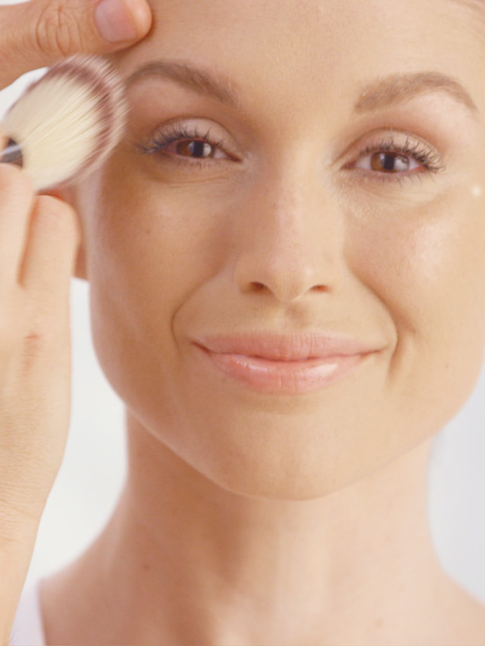 A smiling woman having make up applied